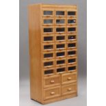 A mid-20th century pale oak haberdashery cabinet by Liddle, Keen & Co, London, fitted with twenty-