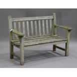 A late 20th century teak garden bench, the slatted seat and back raised on block legs, height