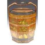 A 20th century Chinese lacquered wooden stacking food carrier, the sides gilded with landscape