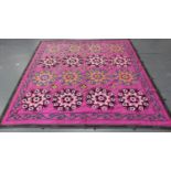 A large Turkish suzani, the magenta silk ground with overall embroidered flowerheads, within a green