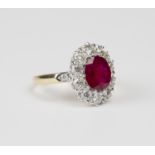 A gold, ruby and diamond oval cluster ring, claw set with the oval cut ruby within a surround of
