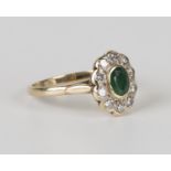 A 9ct gold, emerald and diamond oval cluster ring, mounted with the oval cut emerald within a