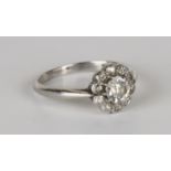A platinum and diamond cluster ring, claw set with the principal cushion shaped diamond within a