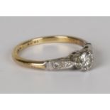A gold, platinum and diamond single stone ring, claw set with a circular cut diamond between diamond