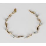 A 9ct gold, blue topaz and diamond bracelet in a serpentine link design, claw set with eight oval