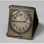 A George V silver cased travelling bedside clock of rectangular form with engine turned