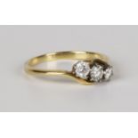 A gold, platinum and diamond three stone ring, claw set with a row of circular cut diamonds with the