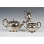 A Victorian silver three-piece tea set of circular form, engraved with flowers and foliate