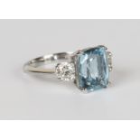 A platinum, aquamarine and diamond three stone ring, claw set with a cushion cut aquamarine