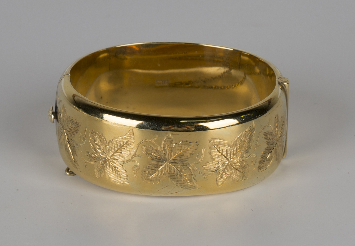 A silver gilt oval hinged bangle, the front engraved with a band of leaves, Birmingham 1960 by