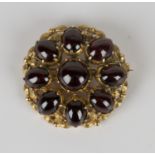 A 9ct gold and carbuncle garnet brooch of shaped circular form, mounted with a circular carbuncle