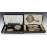 A George V silver backed five-piece dressing table set, comprising a hand mirror, a pair of