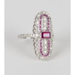 A platinum, ruby and diamond oval panel shaped ring, collet set with an emerald cut ruby between two
