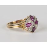 A gold, ruby and diamond circular cluster ring, claw set with four pear shaped rubies centred by a