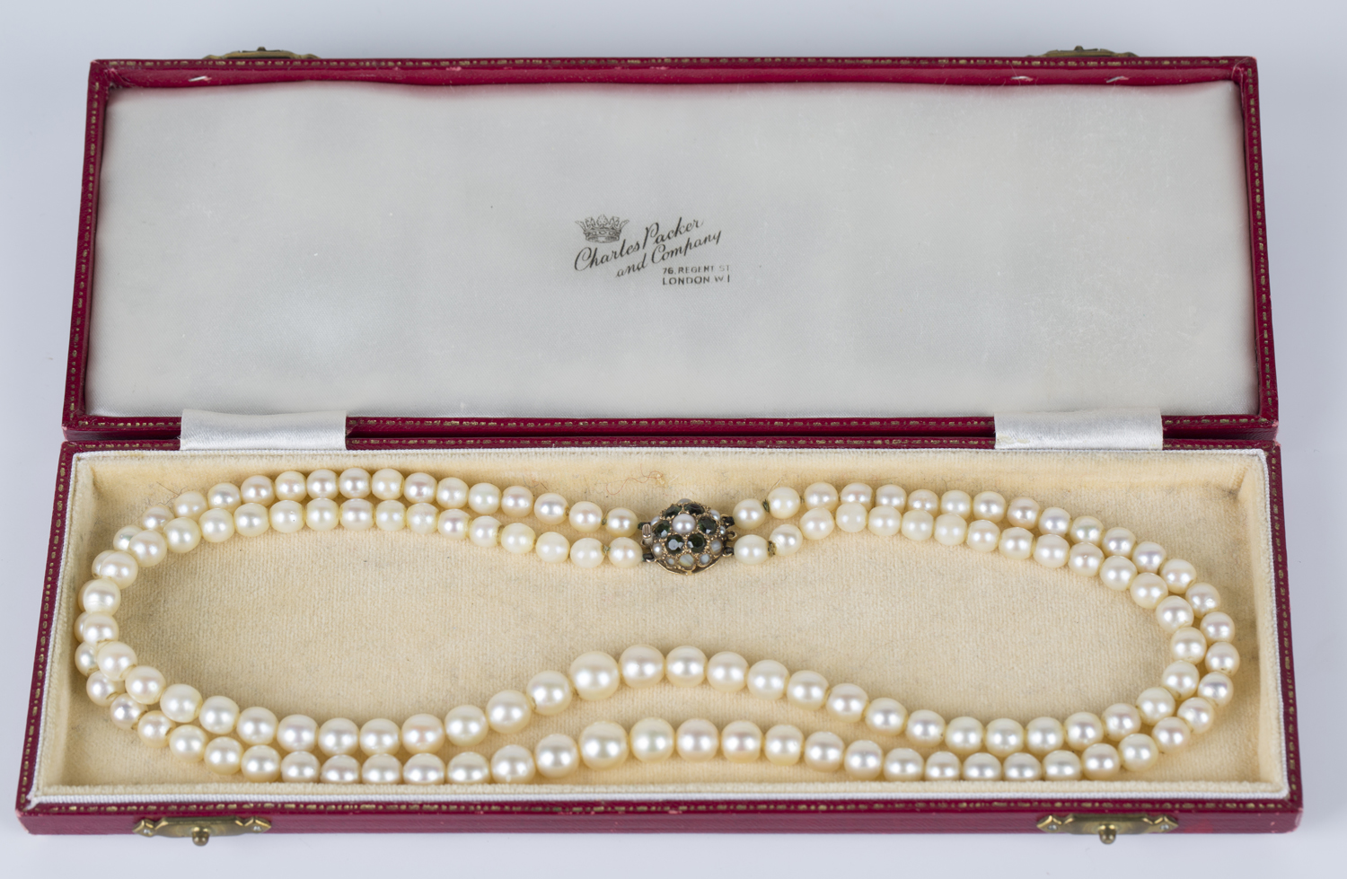 A two row necklace of graduated cultured pearls with a 9ct gold, green gemstone and half-pearl set