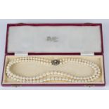 A two row necklace of graduated cultured pearls with a 9ct gold, green gemstone and half-pearl set