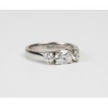 A white gold and diamond three stone ring, claw set with the principal oval cut diamond between