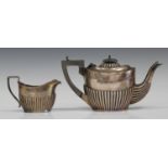 An Edwardian silver bachelor's teapot with half-reeded decoration and a matching milk jug,