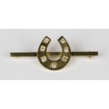 A gold and diamond bar brooch, designed as a horseshoe, mounted with seven cushion shaped