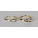 A gold and diamond two stone ring, claw set with cushion shaped diamonds in a cross-over design,