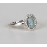 An 18ct gold, aquamarine and diamond oval cluster ring, claw set with the oval cut aquamarine within
