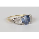 A gold, Ceylon sapphire and diamond ring, claw set with a cushion cut Ceylon sapphire between