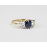 A gold, sapphire and diamond three stone ring, claw set with the oval cut sapphire between two