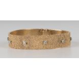 A gold and diamond bracelet, mounted with ten circular cut diamonds on a textured ground, on a
