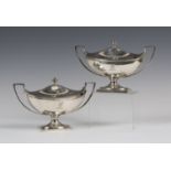 A pair of George III silver oval boat shaped sauce tureens, each domed cover with an urn shaped