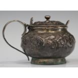 A George III silver circular mustard, the squat body and hinged lid decorated in relief with flowers