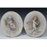 A pair of French porcelain oval wall plaques, circa 1900, allegorical of Autumn and Winter, each