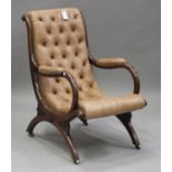 A William IV rosewood library armchair, upholstered in buttoned brown leather, raised on downswept