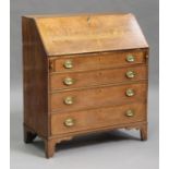 A George III oak bureau, crossbanded in mahogany, the fall flap revealing a fitted interior above