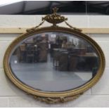 An early 20th century Neoclassical Revival oval gilt framed wall mirror with urn and swag