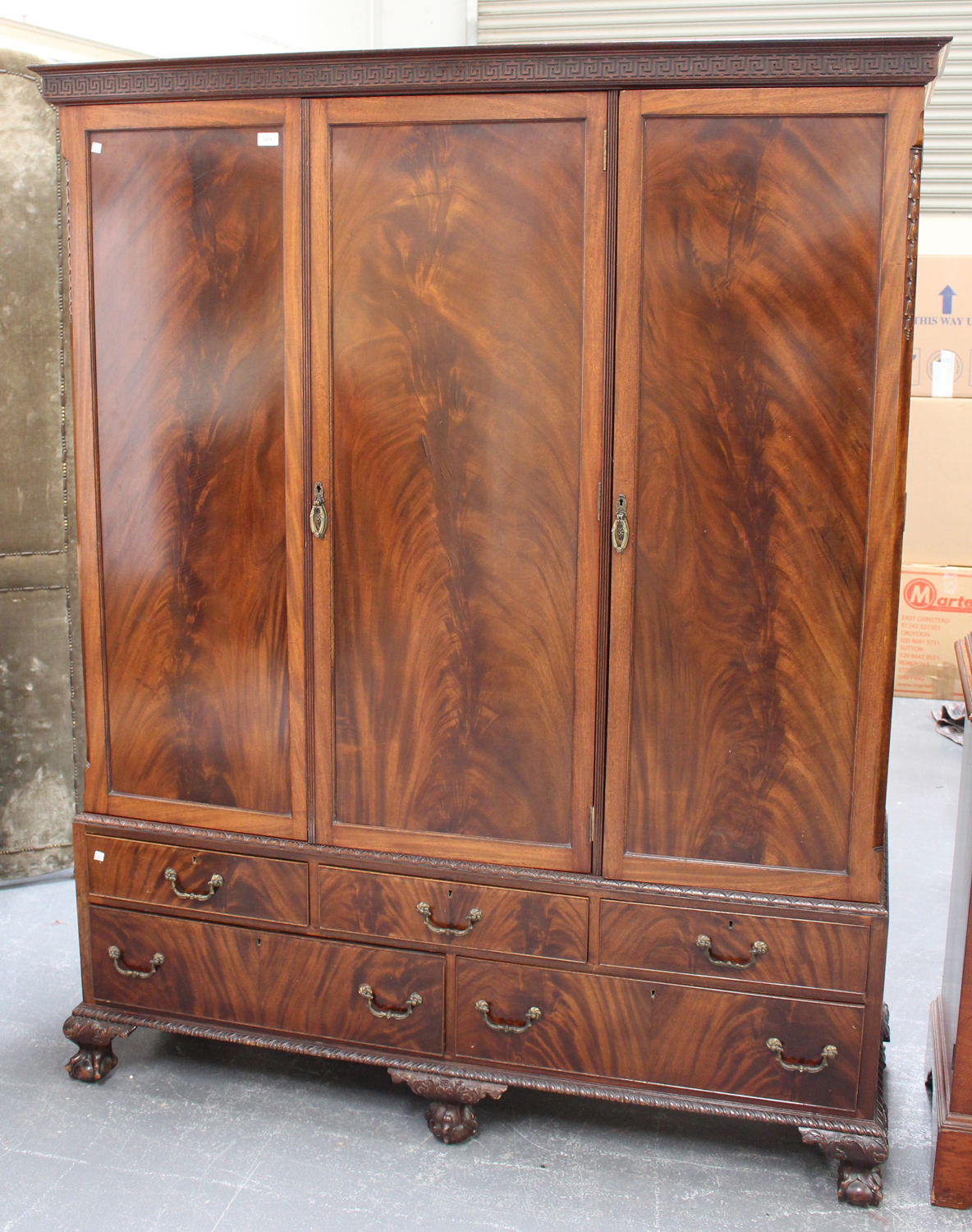 A George V figured mahogany three-section compactum wardrobe, fitted with an arrangement of drawers,