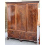 A George V figured mahogany three-section compactum wardrobe, fitted with an arrangement of drawers,