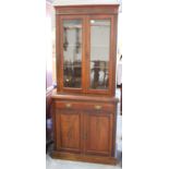 A late Victorian walnut bookcase cabinet, the moulded pediment above a pair of glazed doors, the