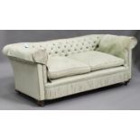 A George V Chesterfield settee, upholstered in a pale green damask, on bun feet and castors,