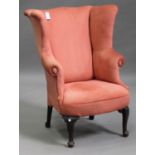 An early 20th century wing back armchair, upholstered in pink velour, on cabriole legs and pad feet,