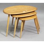 An Ercol elm and beech nest of three occasional tables, the shaped tops raised on turned legs,