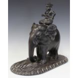 An early 20th century Ceylonese carved ebony model of an elephant and rider, raised on a foliate