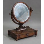 An early 19th century figured mahogany circular swing frame toilet mirror, the base fitted with a