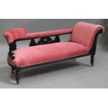 An Edwardian stained beech framed chaise longue, upholstered in pink fabric, on turned legs,