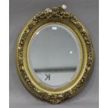 A late 19th century gilt composition oval wall mirror with ribbon and torch surmount, 87cm x 73cm (