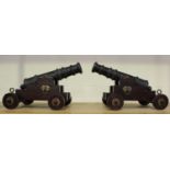 A pair of ornamental bronze cannon, the patinated cast bronze barrels raised on oak and brass