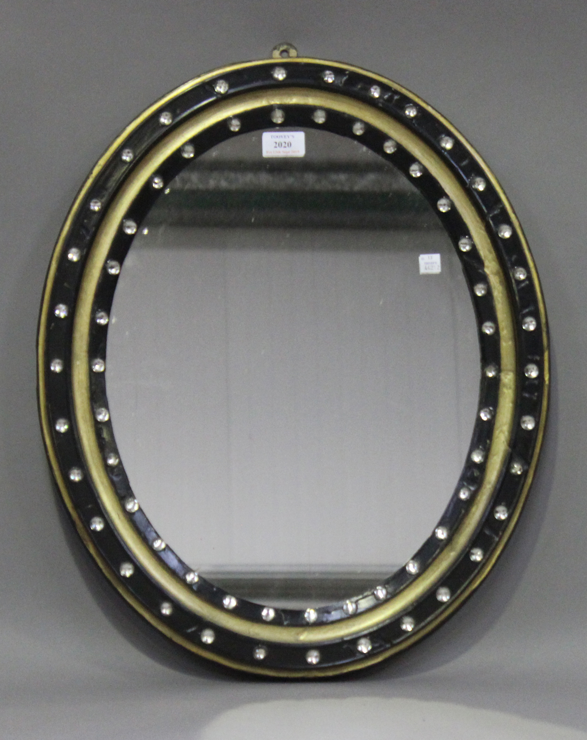 An early 19th century Irish ebonized and gilded oval wall mirror, the frame inset with faceted cut