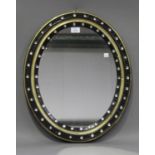 An early 19th century Irish ebonized and gilded oval wall mirror, the frame inset with faceted cut