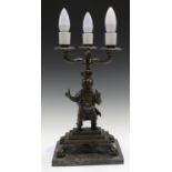 An early 20th century patinated cast bronze figural table lamp, the three scroll branches