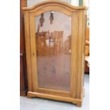 A late 19th/early 20th century French walnut vitrine, the arched top above a glazed panel door, on