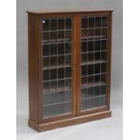 A George V oak bookcase, enclosed by two leaded glazed doors, on a plinth base, height 122cm,
